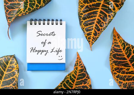 I segreti di una vita felice motivazionale e ispiratore guida scritta su blocco note blu. Bella composizione di posa piatta Foto Stock