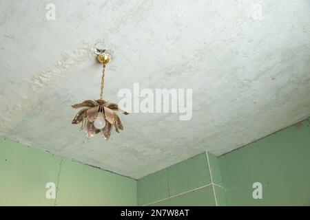 parete in cartongesso verde nella camera durante il rinnovo e sul soffitto c'è un lampadario sporco, ristrutturazione nell'appartamento Foto Stock