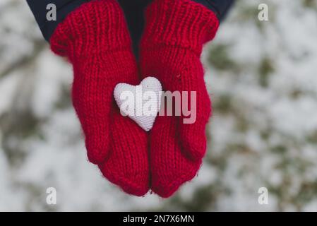 mani con guanti che tengono il cuore bianco Foto Stock
