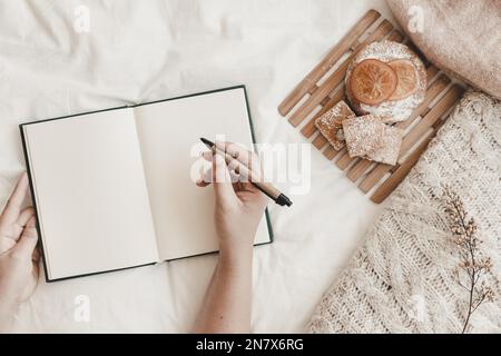 penna per tenere la mano con letto del notebook aperto Foto Stock