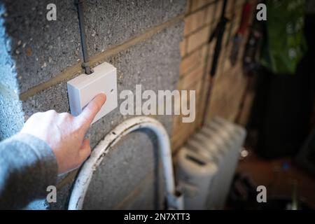 Messa a fuoco superficiale di una persona con il dito per spegnere un interruttore luci in un garage residenziale. Foto Stock