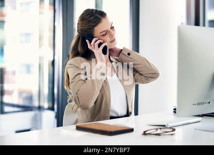 Im non sarà così produttivo oggi. una giovane donna d'affari che guarda stressato mentre parla su un cellulare in un ufficio. Foto Stock