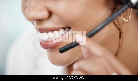 Ora thats servizio con un sorriso. Primo piano di un'irriconoscibile agente di call center femminile che lavora alla sua scrivania in ufficio. Foto Stock