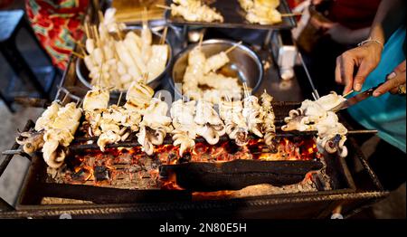 Cibo di strada di polpi fritti e piccanti tailandesi al barbecue al mercato notturno al Capodanno cinese a Bangkok Chinatown in Thailandia Foto Stock