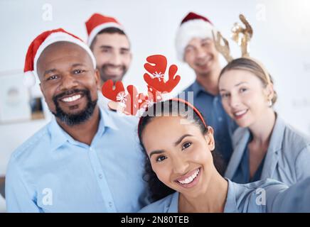 Ritratto di gruppo sorridente di uomini d'affari diversi che prendono selfie in ufficio con cappello di Natale. Buon team di professionisti e colleghi che prendono Foto Stock