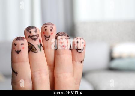 Cinque dita con disegni di volti felici su sfondo sfocato Foto Stock
