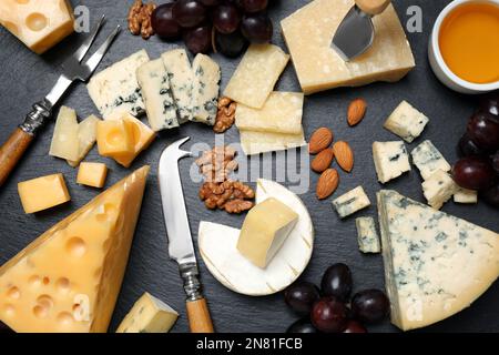 Piatto di formaggi con coltello specializzato e forchetta su tavolo nero, piatto Foto Stock