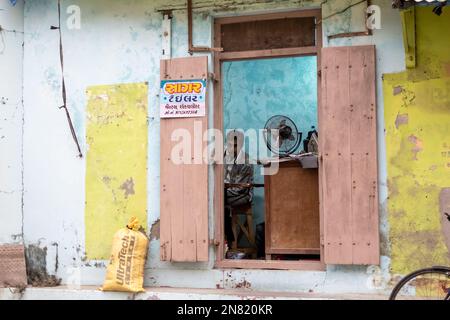 Diu, India - Dicembre 2018: Un sarto che lavora all'interno di un negozio colorato in un edificio rustico nella città di Diu. Foto Stock