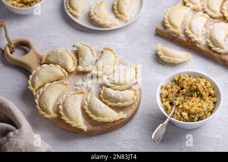 Gnocchi di vegan surgelati fatti in casa, vareniki, pierogi, kreplach ripieni di lenticchie vegane 'mangia', carote, cipolle, erbe aromatiche e spezie su tavola di legno Foto Stock