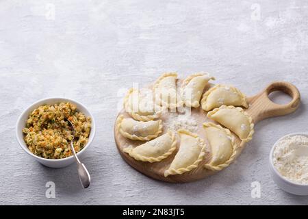 Gnocchi di vegan surgelati fatti in casa, vareniki, pierogi, kreplach ripieni di lenticchie vegane 'mangia', carote, cipolle, erbe aromatiche e spezie su tavola di legno Foto Stock