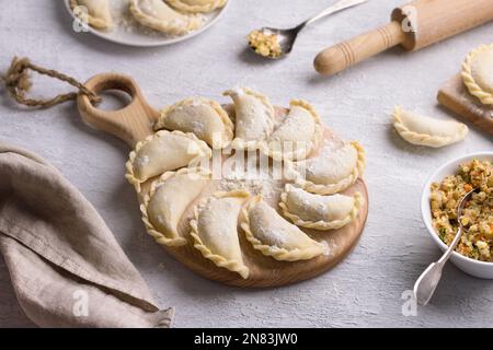 Gnocchi di vegan surgelati fatti in casa, vareniki, pierogi, kreplach ripieni di lenticchie vegane 'mangia', carote, cipolle, erbe aromatiche e spezie su tavola di legno Foto Stock