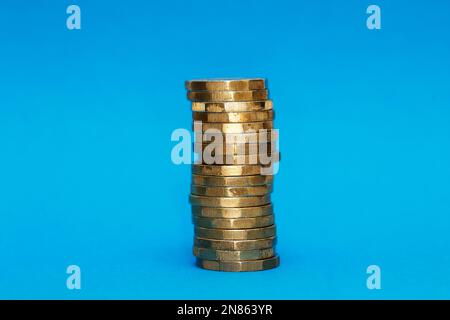 Pila di 18 monete da una libbra su sfondo azzurro Foto Stock