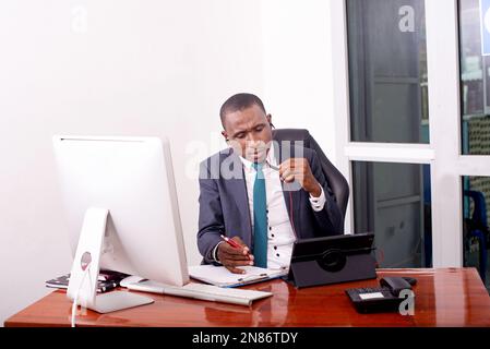 uomo d'affari che lavora in ufficio mentre effettua una videochiamata sul tablet digitale e prende appunti in un documento. Foto Stock