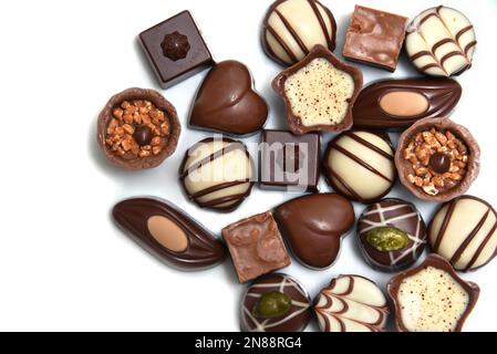 Primo piano di una selezione di cioccolatini di lusso, con una varietà di forme tra cui un cuore, fiorentine e pistacchi. Foto Stock