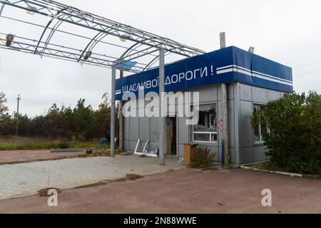 Stazione di servizio danneggiata dalla conchiglie. Iscrizione sull'edificio - "Happy Road". Guerra in Ucraina. Invasione russa dell'Ucraina. Distruzione delle infrastrutture Foto Stock