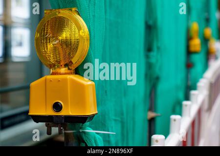 Spia gialla sullo sfondo di una recinzione verde di un cantiere. Primo piano. Foto Stock