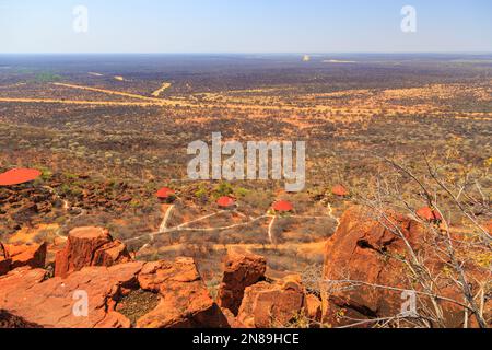 Tetti rossi del Waterberg Plateau Lodge in Namibia si annidano in alto sul pendio di Waterberg con vista attraverso l'infinito Kalahari. Namibia. Foto Stock