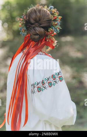 Una bella ragazza Ucraina che indossa un abito ricamato. Una donna con una corona di fiori sulla testa. Foto Stock