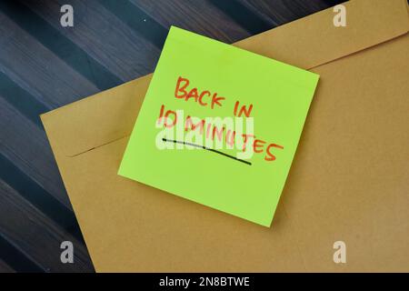 Concetto di ritorno in 10 minuti scrivere su note appiccicose isolate su tavolo di legno. Foto Stock