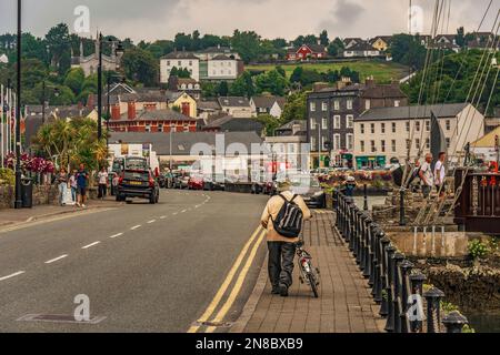 Uomo con bicicletta a piedi a Pier Road a Kinsale. Co Cork, Irlanda. Foto Stock