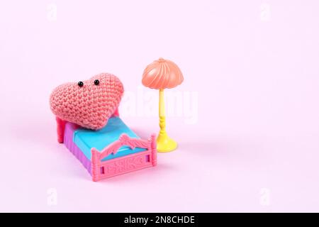 Cuore a maglia rosa con un viso carino si rilassa sul letto. Concetto di amore. Storia di vita in scena di un cuore nella sua stanza Foto Stock