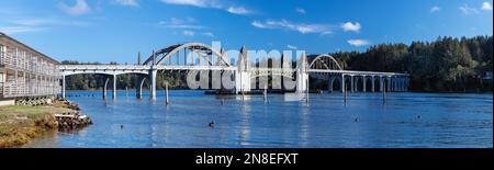 Vista panoramica sul ponte sul fiume Siuslaw e sugli edifici sulla riva sinistra, in un pomeriggio di sole Foto Stock