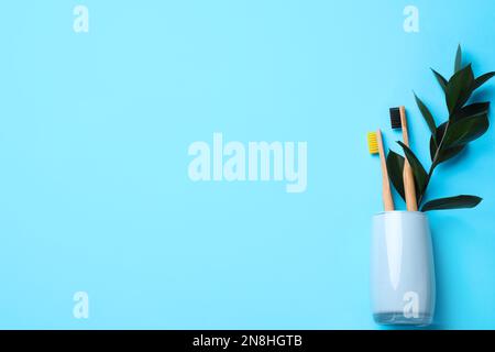 Supporto con spazzolini da denti in bambù su sfondo azzurro, vista dall'alto. Spazio per il testo Foto Stock