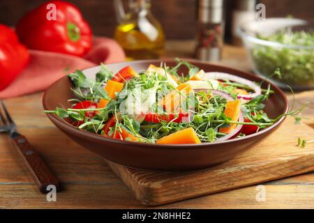 Deliziosa insalata di verdure con microgreens servita su un tavolo di legno Foto Stock