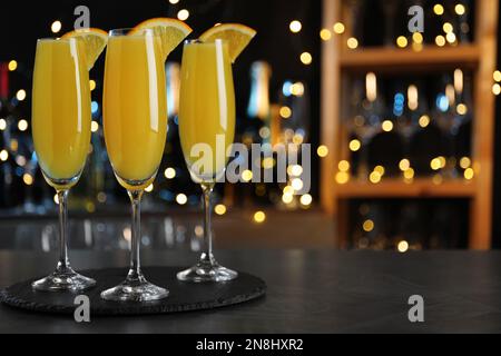 Cocktail Mimosa con decorazione sul bancone del bar contro le luci sfocate, spazio per il testo Foto Stock