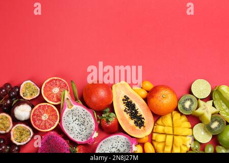 Molti deliziosi frutti esotici diversi su sfondo rosso, piatto. Spazio per il testo Foto Stock