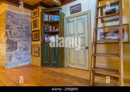 Corridoio con ampie pavimentazioni in legno di pino, scale di Miller, libreria e porta della camera da letto in difficoltà al piano superiore all'interno del vecchio 1805. Foto Stock