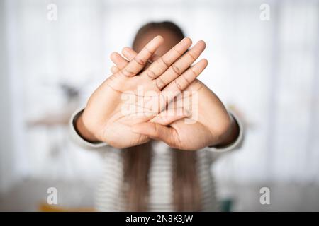 Donna nera irriconoscibile che si nasconde dietro le mani Foto Stock