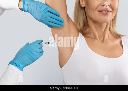 Il medico effettua iniezioni intramuscolari nella zona delle ascelle Foto Stock