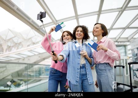 Ritratto di tre donne felici che scattano foto insieme all'aeroporto Foto Stock