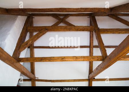 Soffitto bianco in ghisa e struttura originale in legno che mostra travi con giunti mortis e tenone in soffitta all'interno della vecchia casa di regime francese del 1809. Foto Stock