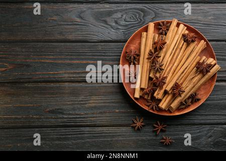 Cannella aromatica e anice su tavolo di legno nero, piatto. Spazio per il testo Foto Stock