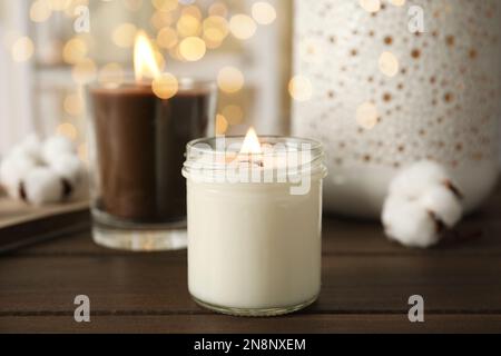 Candele bruciate in porta vetro su tavola di legno Foto Stock