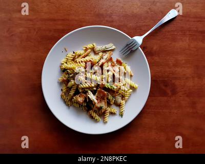 Fusilli cotto con fettine di carne fritte servite con erbe e spezie Foto Stock