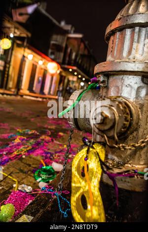 Idrante di fuoco e strada abbellita di perline, maschera e lettiera dopo una sfilata di Mardi Gras Foto Stock