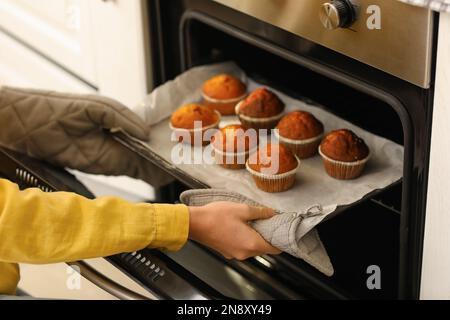 Chef donna che prende la farina di grano dal recipiente di vetro e  setacciando sul tavolo. Panettiere senior pensionato con bonete e uniforme  irrorazione, setacciatura, spalmatura di ingredienti rew cottura di pizza