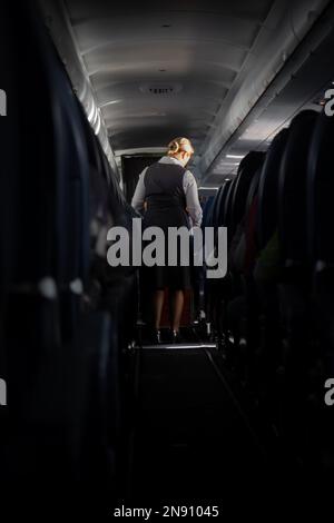 La hostess serve rinfreschi a bordo dell'aeromobile. Vista sul corridoio dell'aereo. Foto Stock