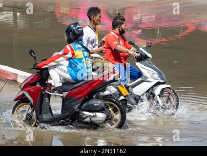 SAMUT PRAKAN, THAILANDIA, 25 2023 GENNAIO, la gente cavalca i motocicli attraverso le pozzanghere sulla strada Foto Stock