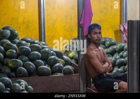 Un giovane cambogiano vende anguria al principale mercato all'ingrosso di verdure e carne, Phsar Dumkor, di notte a Phnom Penh, Cambogia. © Kraig Lieb Foto Stock