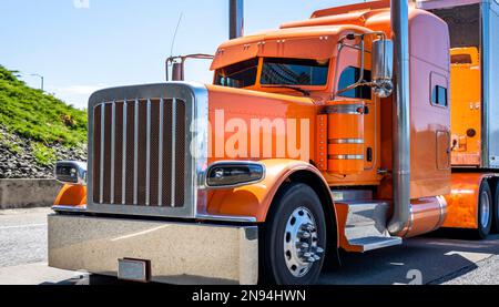 Trattrice industriale classico americano a lunga lunghezza carro grande arancione con cabina estesa per il riposo del conducente del camion che trasporta il carico commerciale a secco Foto Stock