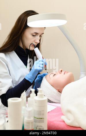 Un cosmetologo esegue una procedura di ringiovanimento mesoterapico con l'aiuto di dermapen, una visita ad un cosmetologo. Foto Stock