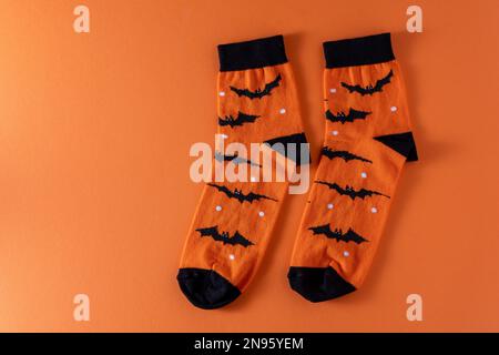 Calzini arancioni con pipistrelli. Costume di abbigliamento per la festa di Halloween. Vista dall'alto della calza vivace e multicolore. Spazio di copia. Foto Stock