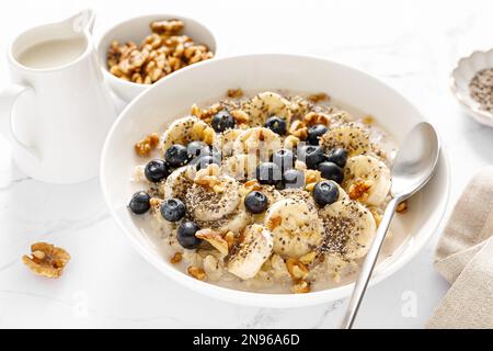 Ciotola di farina d' Porridge di avena con banana, mirtillo, noce, semi di chia e latte di avena per una sana colazione. Alimentazione sana Foto Stock