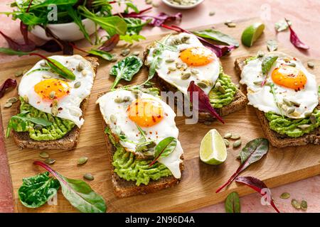 Toast all'uovo e all'avocado, panini con uova e verdure fresche. Alimentazione sana Foto Stock