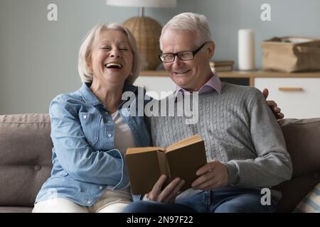 Allegra coppia anziana di pensionati che leggono insieme un romanzo classico divertente Foto Stock