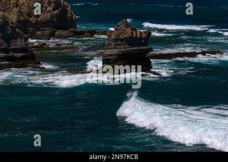 Aspettate che la marea sia fuori: Una scala di corda crudelmente fatta ad anello intorno alla cima di un pilastro del mare o una roccia stack in mezzo al surf Atlantico in salita sulla punta di Cabo Carvoeiro vicino a Peniche nel distretto di Leiria, Portogallo centrale, offre agli sciocchezze e agli appassionati di sport pericolosi una sfida alternativa e pericolosa. Foto Stock